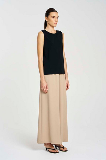 Woman wearing a black sleeveless top and beige wide-leg pants on a white background