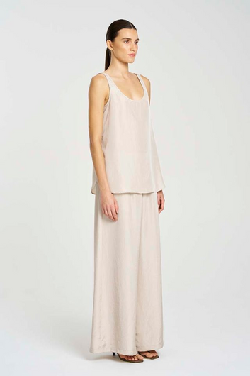 Woman wearing a light pink sleeveless top and long skirt on a white background