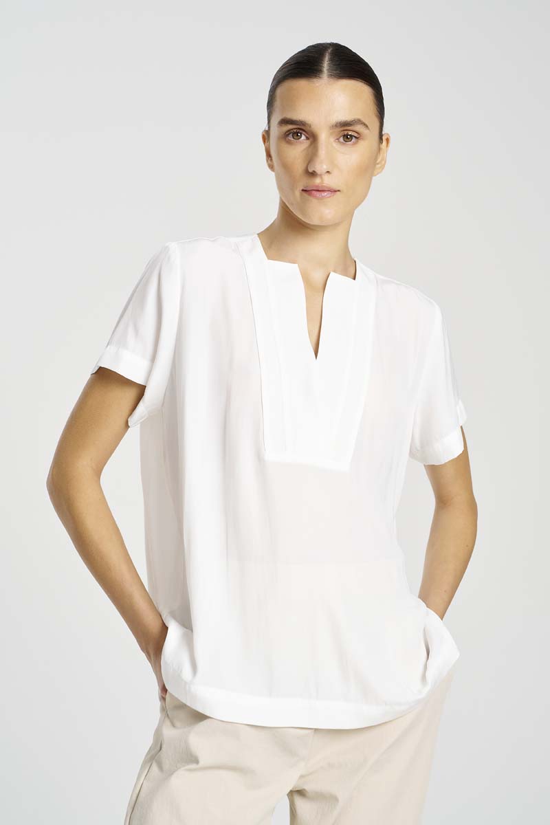 Person wearing a white blouse and beige pants on a plain background
