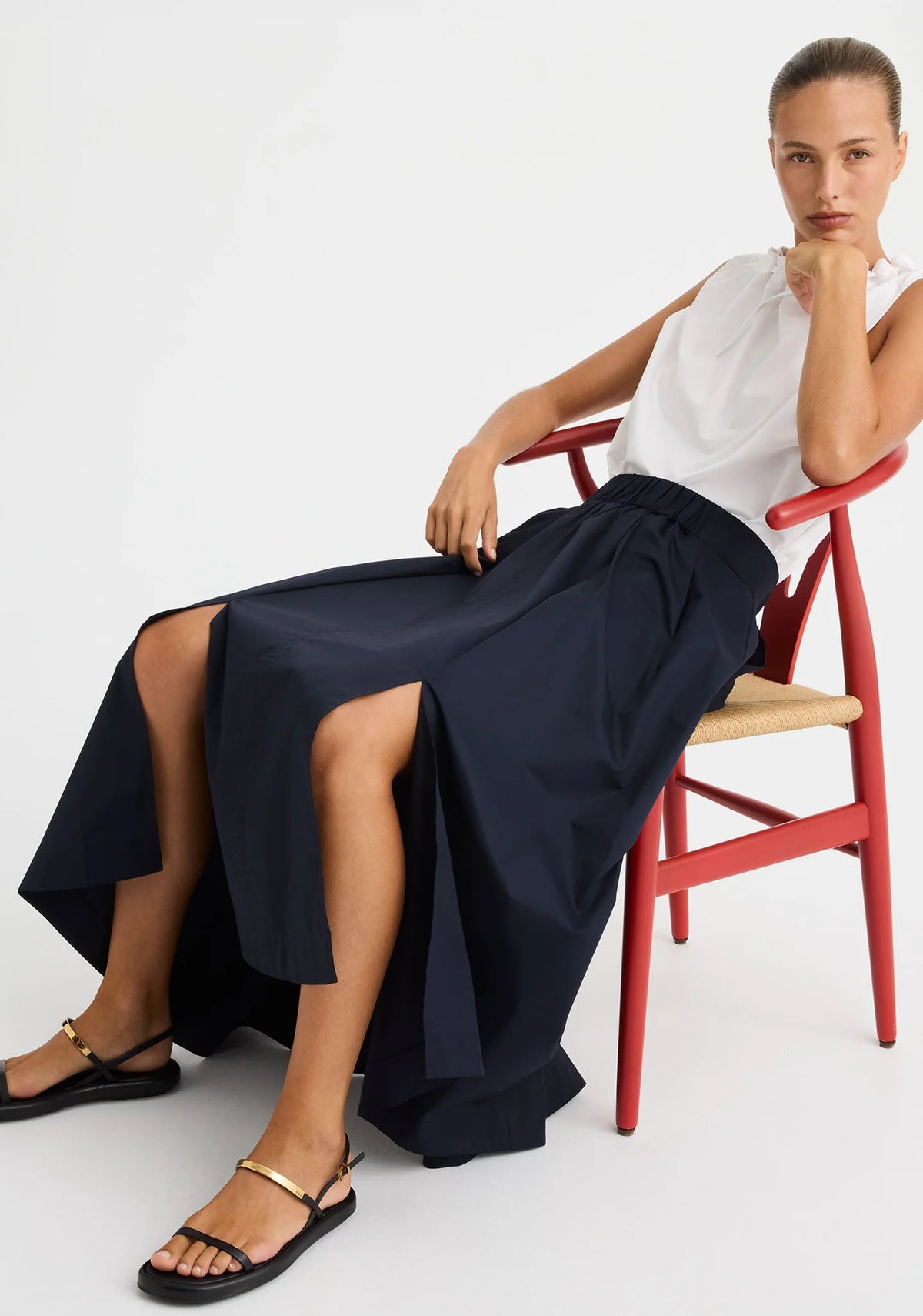 Morrison Maddison Skirt in Navy, styled seated showing the full skirt and split